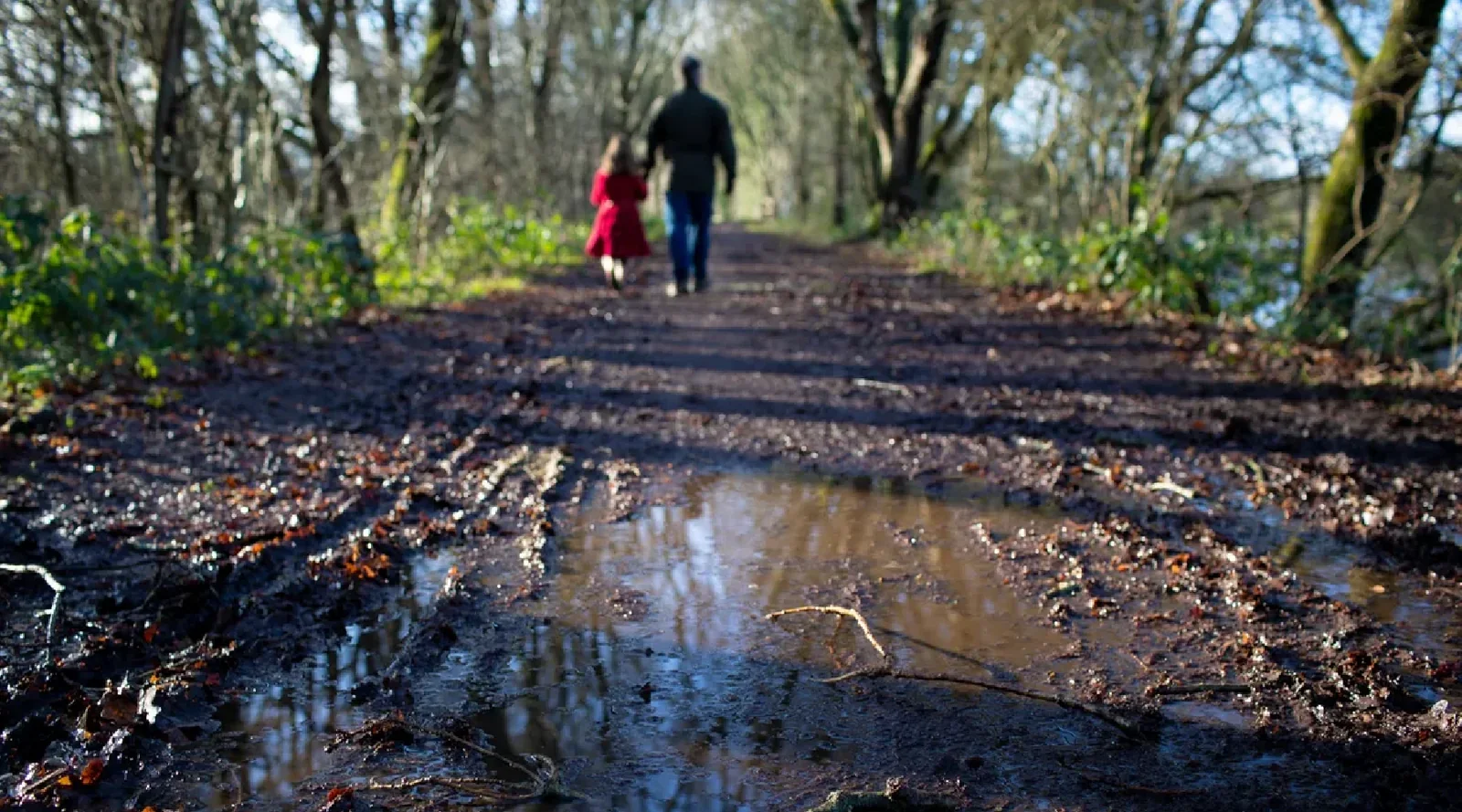 Dos personas caminando por un sendero embarrado en un bosque