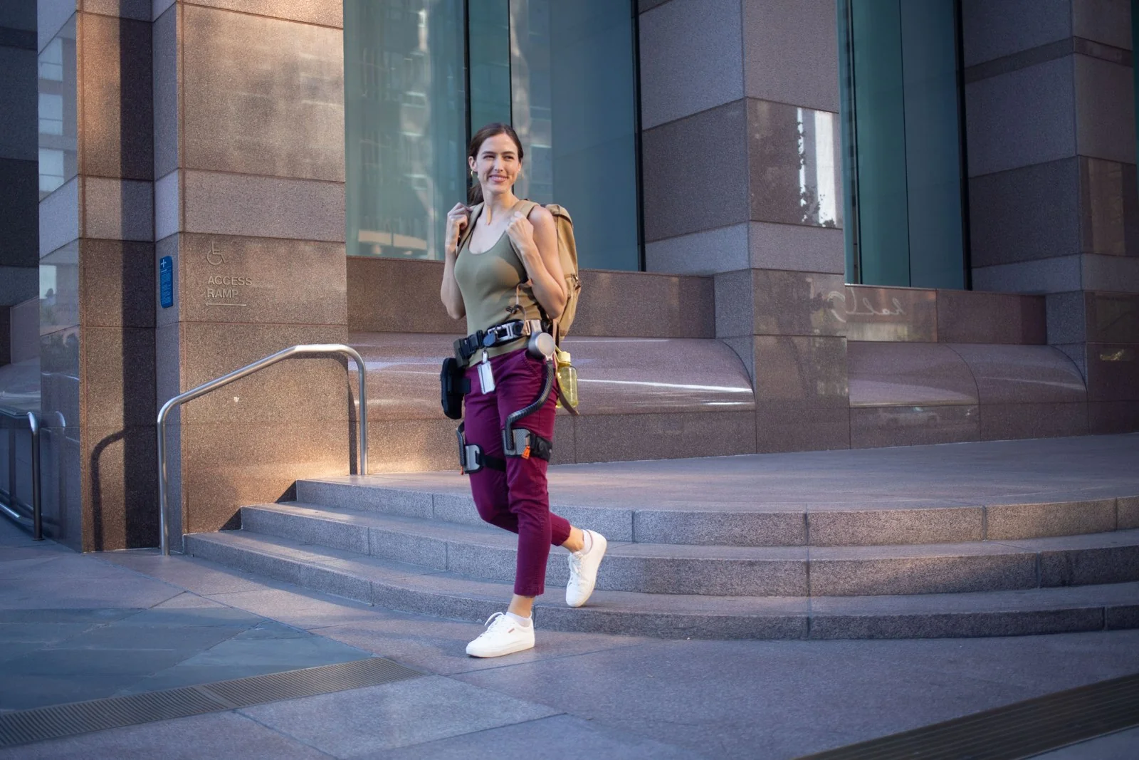 Una mujer con un exoesqueleto de cadera Ascentiz camina junto a unas escaleras exteriores.