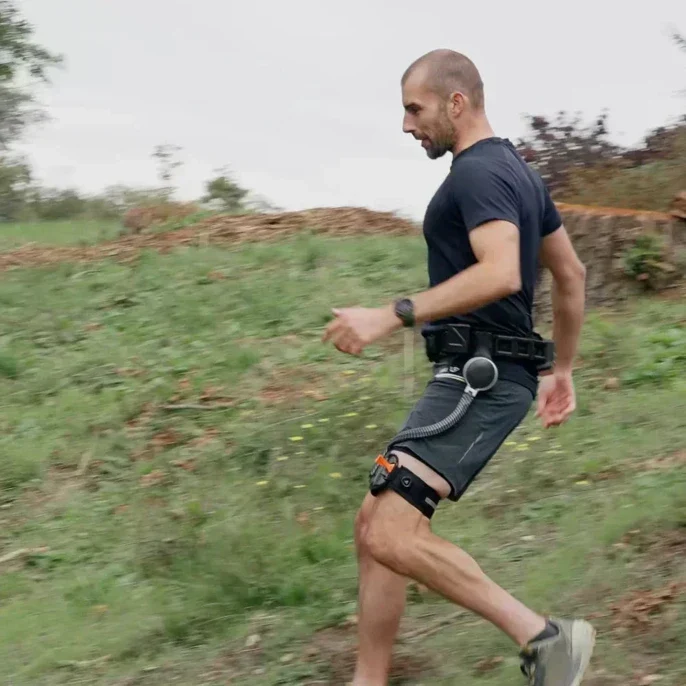 A man running down a slope outdoors with a pair of Ascentiz robotic legs attached.