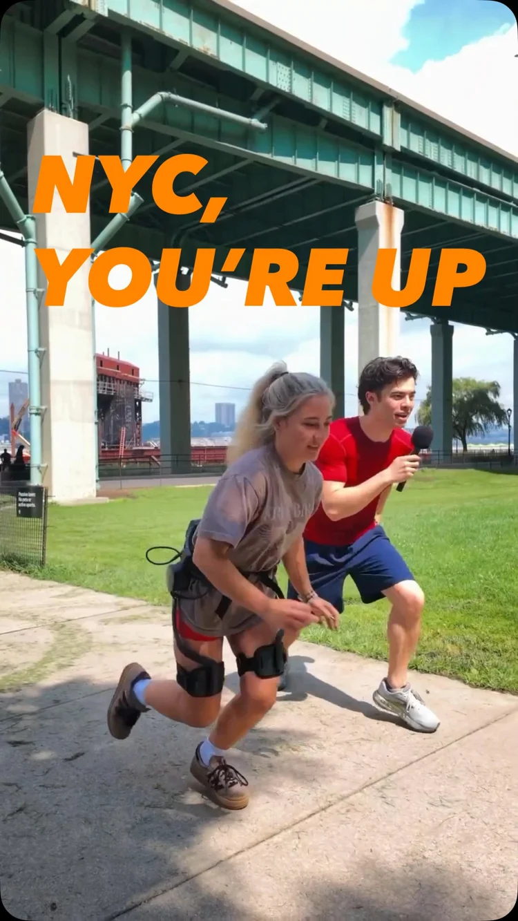 Two people running outdoors, while one of them is wearing a hip exoskeleton from Ascentiz.